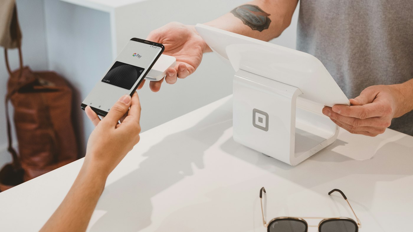 A customer holding a phone to a card terminal to pay