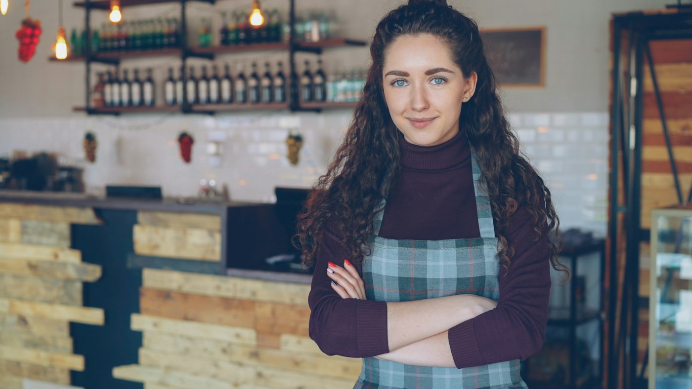 A small business owner standing behind the counter of her coffee shop