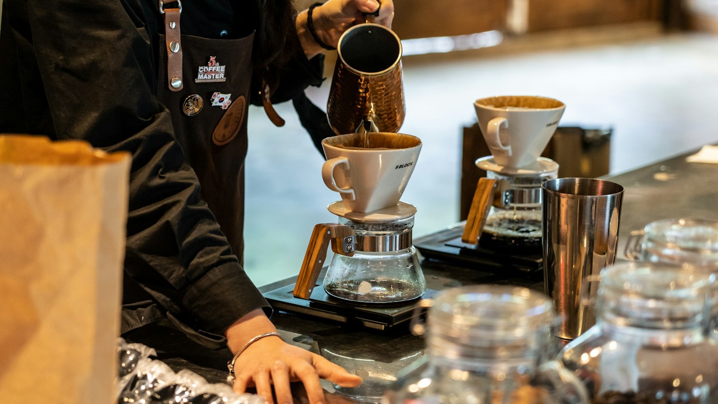 A barista pouring coffee into a cup